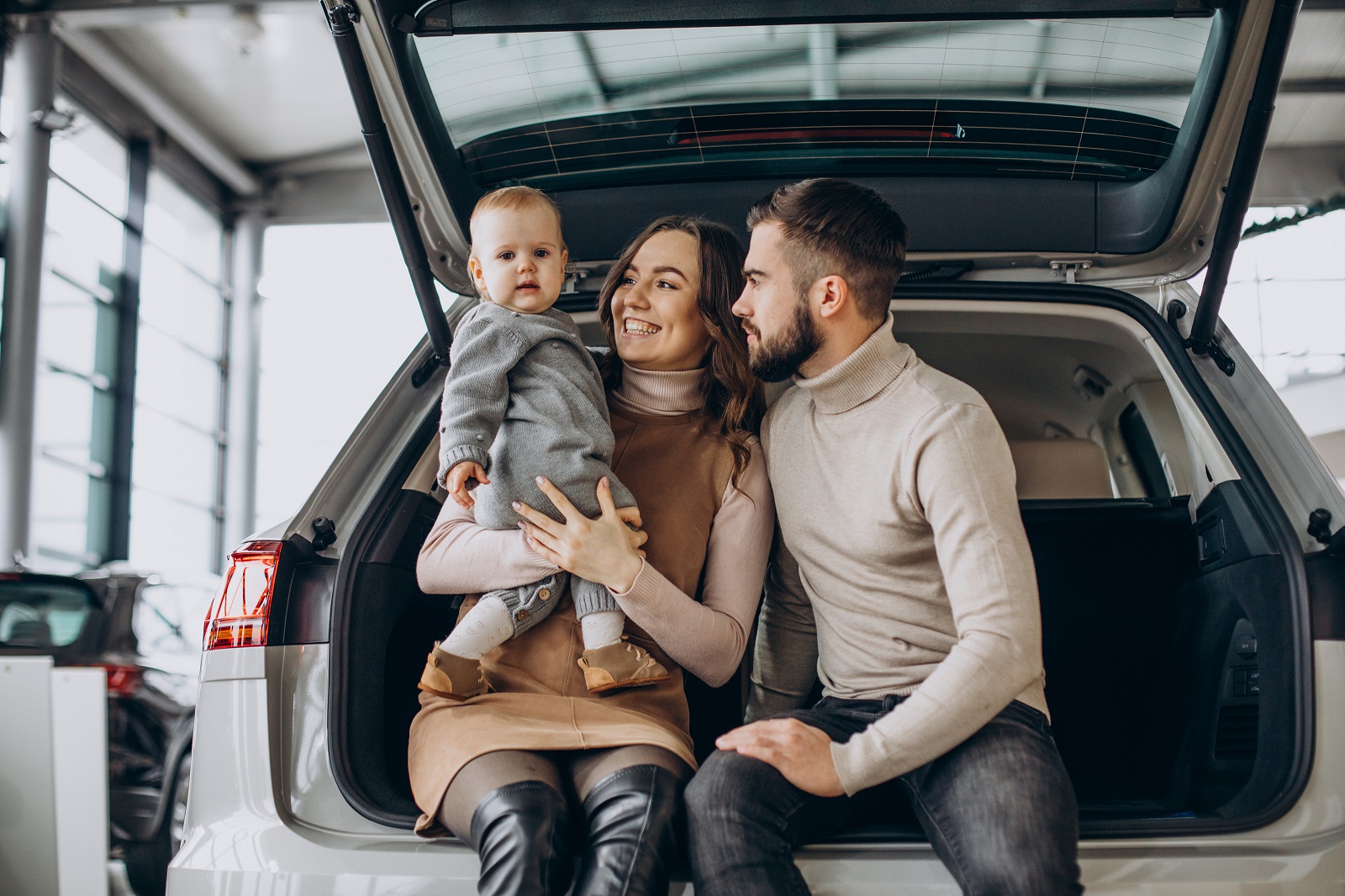 Family with toddler girl choosing a car in a car showroom